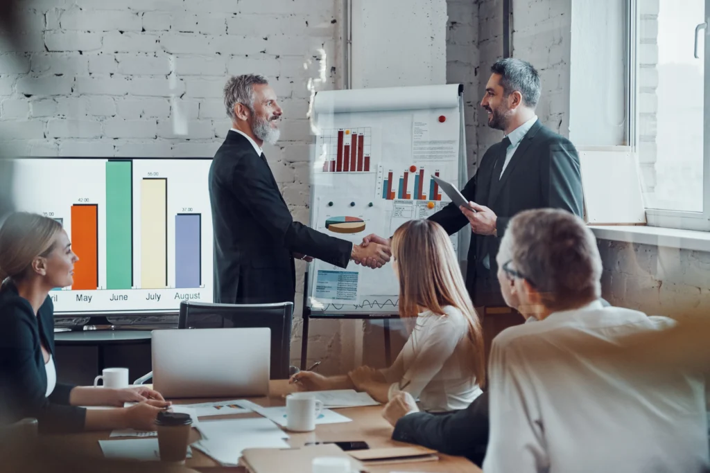 serviços-Consultoria-Avaliação-diagnóstica-empresarios-modernos-apertando-as-maos-enquanto-trabalham-juntos-com-sua-equipe-na-sala-da-diretoria